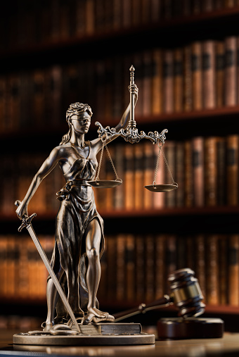 legal concept: themis is the goddess of justice and the judge's gavel hammer as a symbol of law and order on the background of books